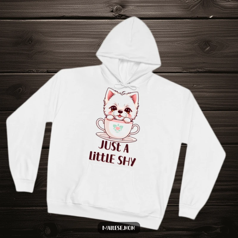 Funny Maltese Dog Hoodie: A shy Maltese dog peeks from behind a tiny teacup, offering warmth and endearing cuteness.