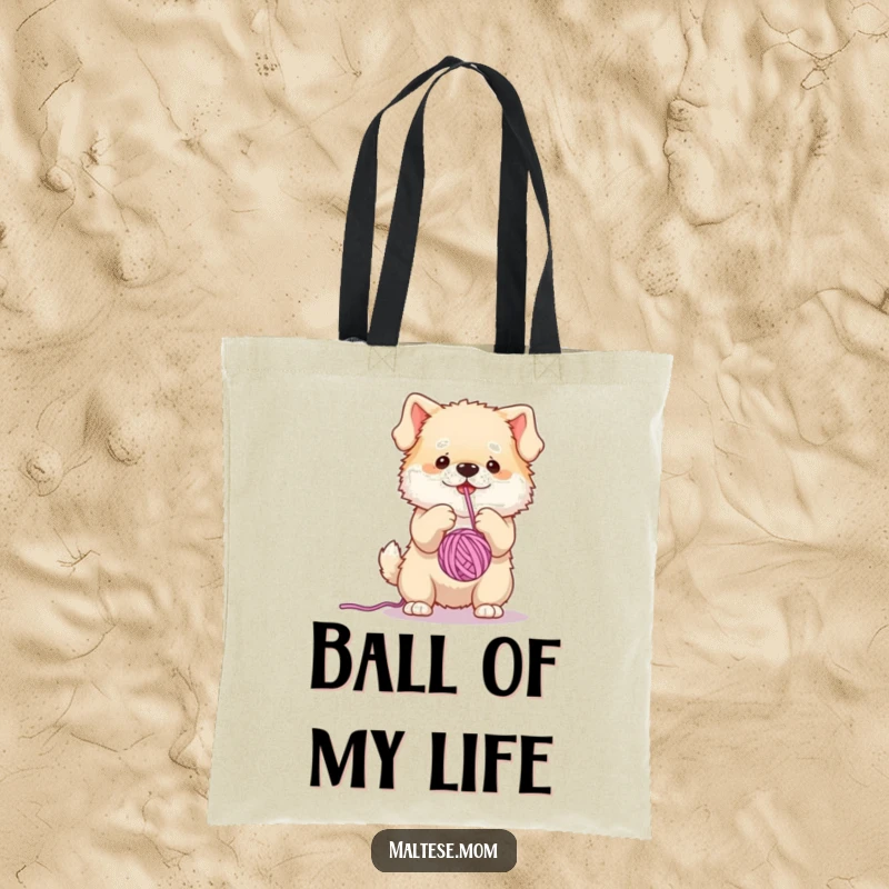 Funny tote bag showcasing a small, fluffy dog character hilariously engaged in batting a dangling yarn ball, perfect for daily use.